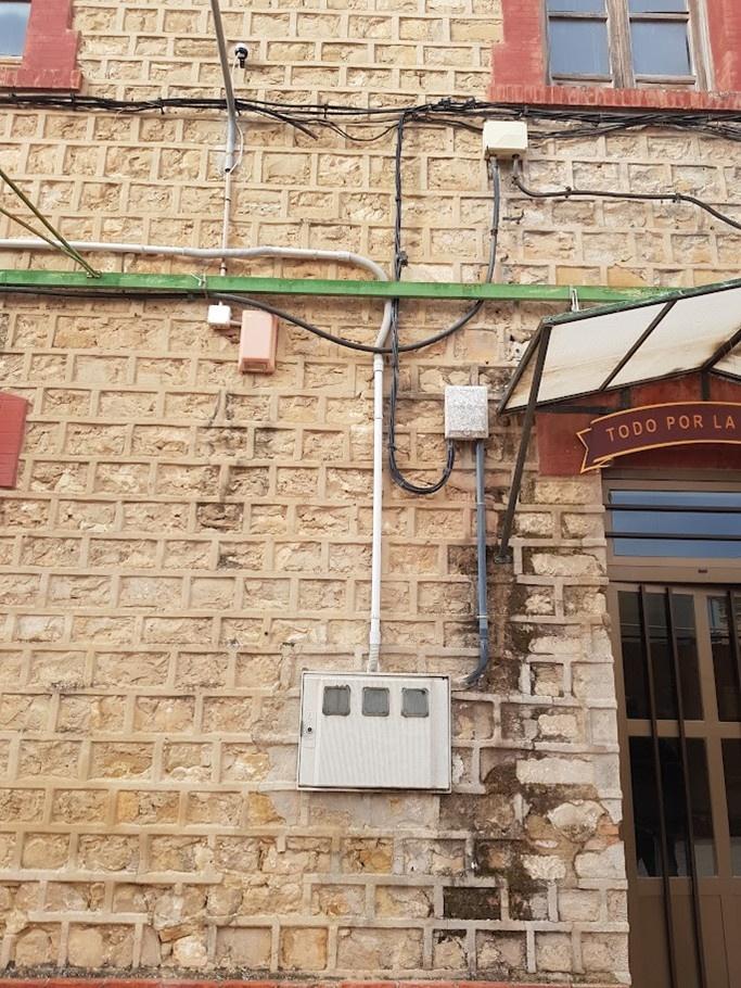 Instalación eléctrica exterior en la fachada de un edificio de la Guardia Civil en Jaén, con cableado y cuadro de conexiones como parte de la ampliación de líneas de enlace.